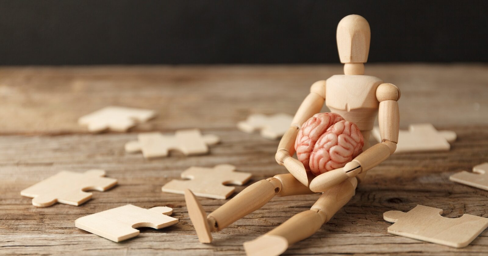toy man sits with brain and puzzle pieces