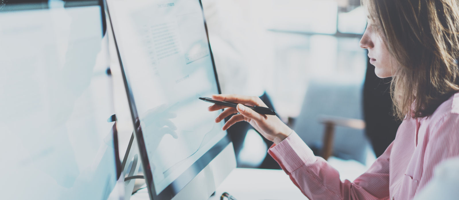 A female student works on spreadsheets on a large computer monitor