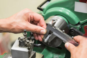 Gloved hand holding a laboratory flask with blue liquid in a chemical engineering lab setting