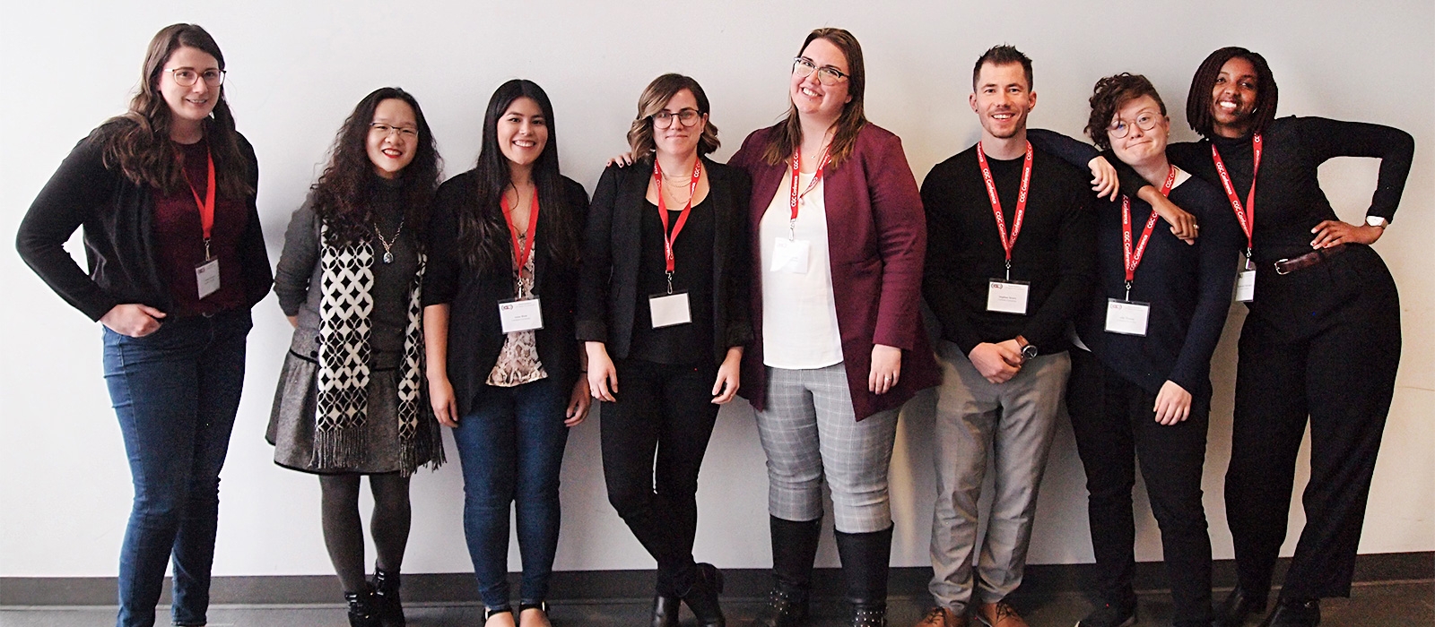 A group of very happy students of a range of racialized groups and gender identities, smiling for the camera with one of their professors.