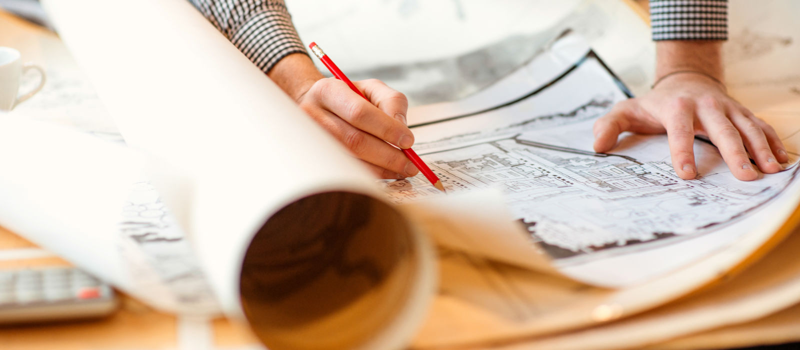 A person alters an architectural plan using a pencil. 