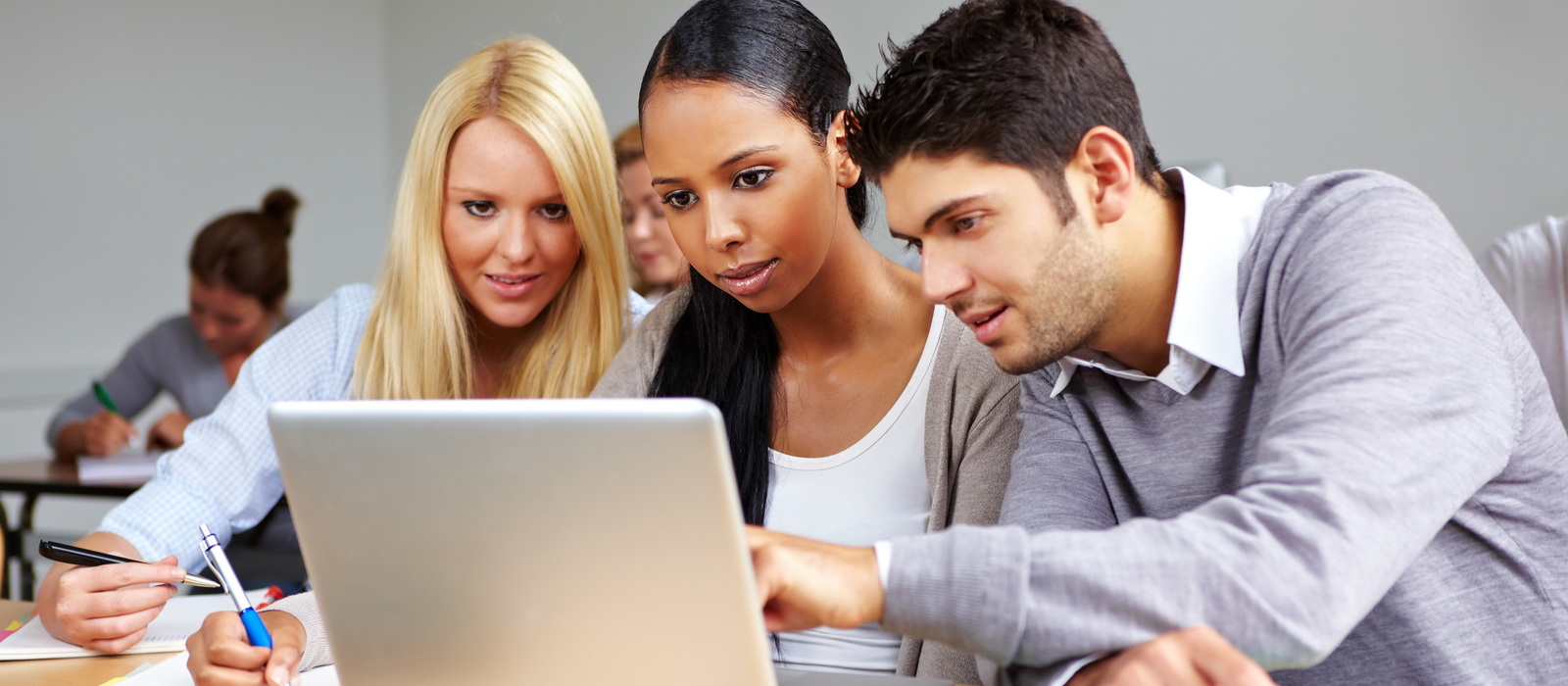 Two women, one white and one black, and a white man analyse a problem on a computer screen.