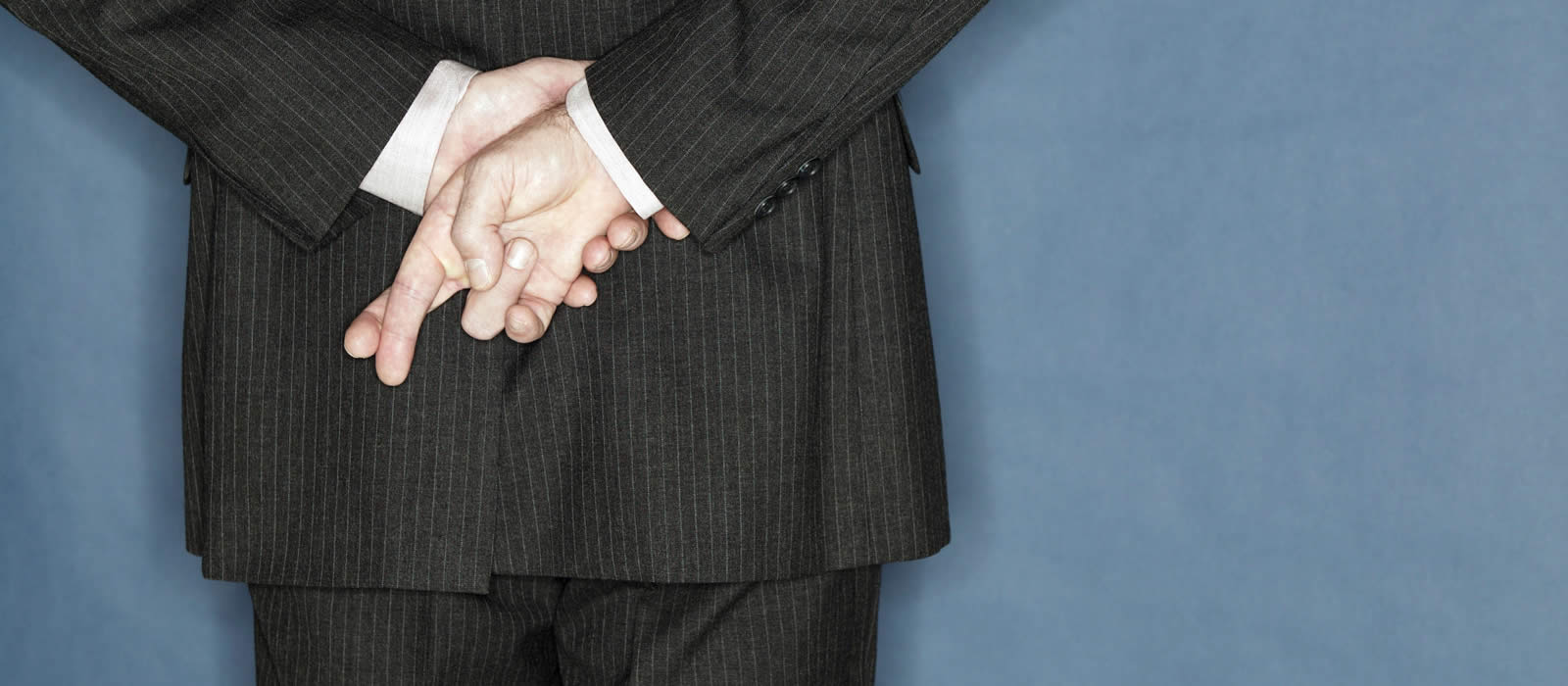 Businessman with fingers crossed behind his back